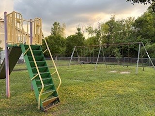 A playground with a green slide and a swing set.